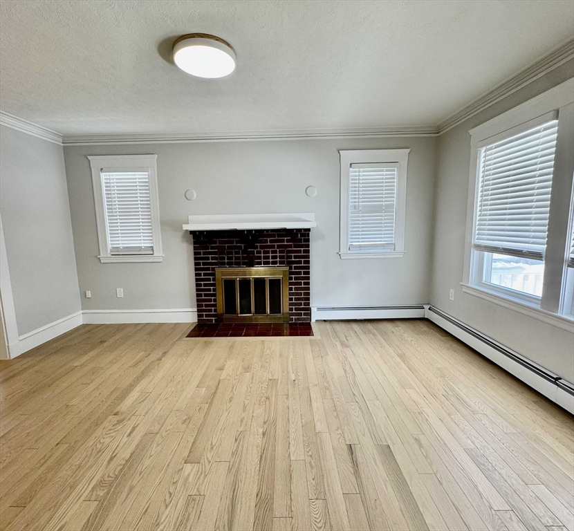 42 Chester Road, Unit 1 Belmont, MA 02478 - Photo 9 of 22 an empty room with wooden floor fireplace and windows