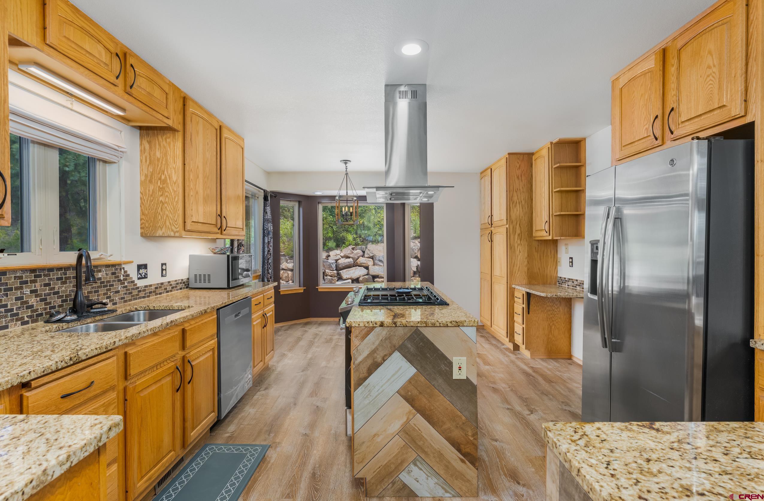 197 Buckhorn Road Bayfield, CO 81122 - Photo 7 of 34 a large kitchen with stainless steel appliances kitchen island granite countertop a refrigerator a sink dishwasher a stove and white countertops with wooden floor