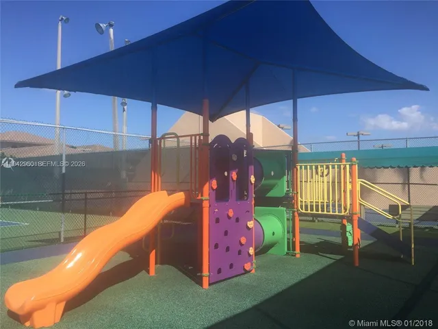 a backyard of a house with table and chairs under an umbrella