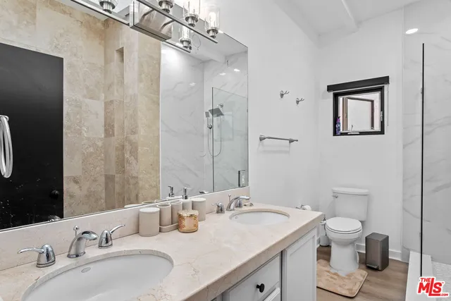 a bathroom with a granite countertop sink a toilet and a mirror