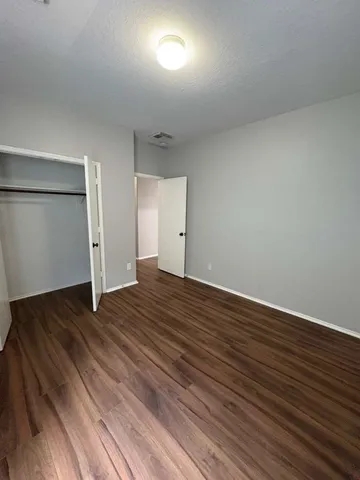 a view of an empty room with wooden floor and closet