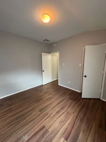 a view of an empty room with wooden floor and closet