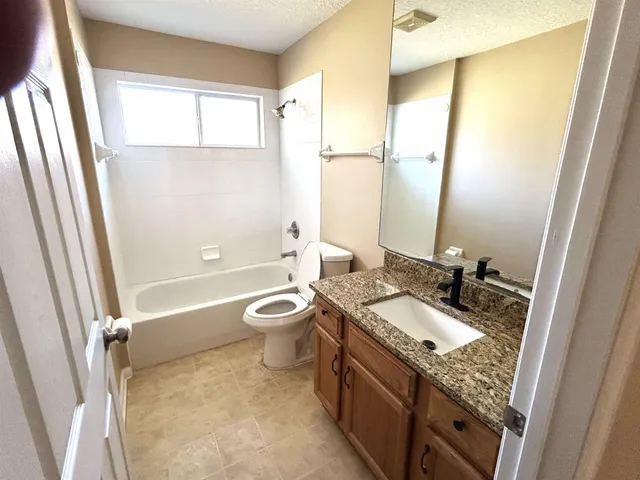 a bathroom with a granite countertop sink toilet and shower a mirror