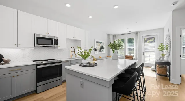 a kitchen with a stove a sink a microwave a dining table and chairs