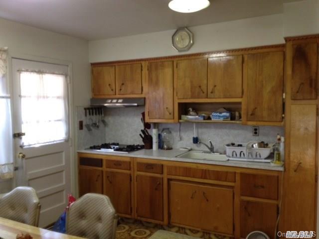 135-47 124th Street Queens, NY 11420 - Photo 14 of 17 a kitchen with stainless steel appliances a sink a stove a refrigerator cabinets and a window