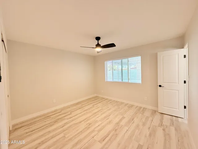 a view of empty room with wooden floor and fan