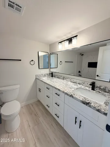 a bathroom with a granite countertop sink mirror and toilet