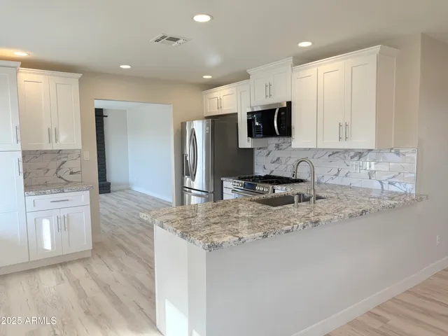 a kitchen with stainless steel appliances granite countertop a refrigerator and a stove top oven