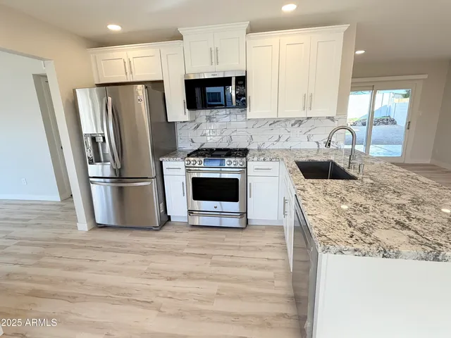 a kitchen with stainless steel appliances granite countertop a refrigerator stove and sink