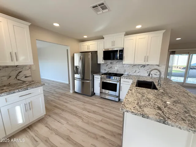 a kitchen with stainless steel appliances granite countertop a stove top oven a sink and a granite counter tops