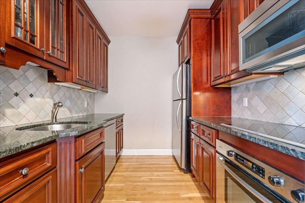 130 Appleton Street, Unit 4E Boston, MA 02116 - Photo 6 of 17 a kitchen with stainless steel appliances granite countertop a sink and dishwasher a stove top oven with wooden floor