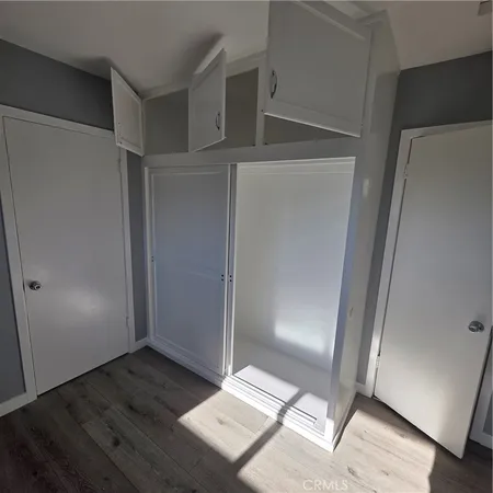 an empty room with wooden floor door and windows