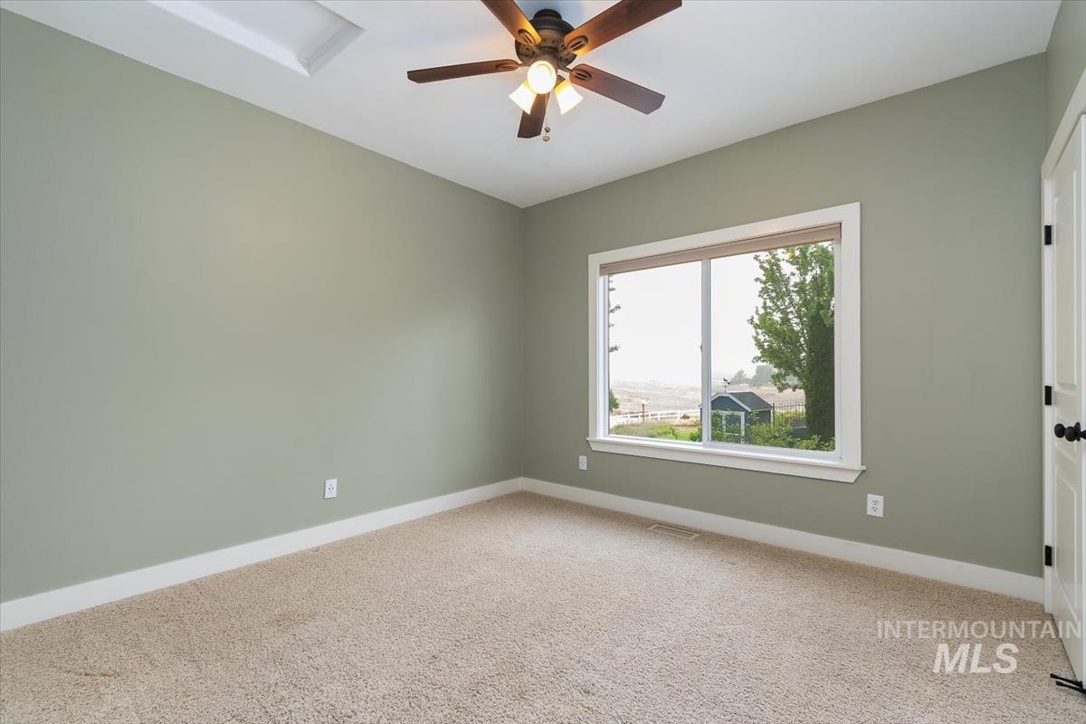 10462 West Lanktree Gulch Road Star, ID 83669 - Photo 24 of 48 Carpeted room featuring a ceiling fan with light fixture, tray ceiling, and a large window with white trim