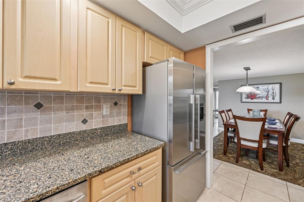 8710 Midnight Pass Road, Unit 203 Sarasota, FL 34242 - Photo 12 of 41 a kitchen with granite countertop a refrigerator and wooden cabinets