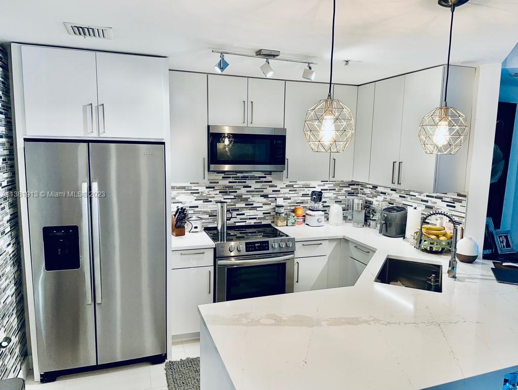 801 Brickell Key Boulevard, Unit 908 Miami, FL 33131 - Photo 6 of 29 a kitchen with stainless steel appliances kitchen island granite countertop a refrigerator a stove a microwave oven a sink a dining table and chairs