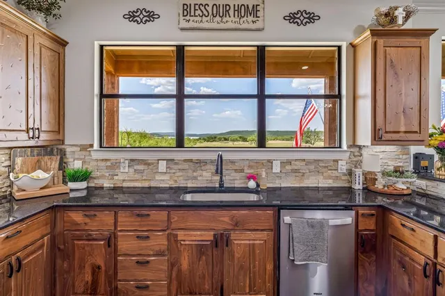 a kitchen with stainless steel appliances granite countertop a refrigerator a stove and a sink with wooden floor