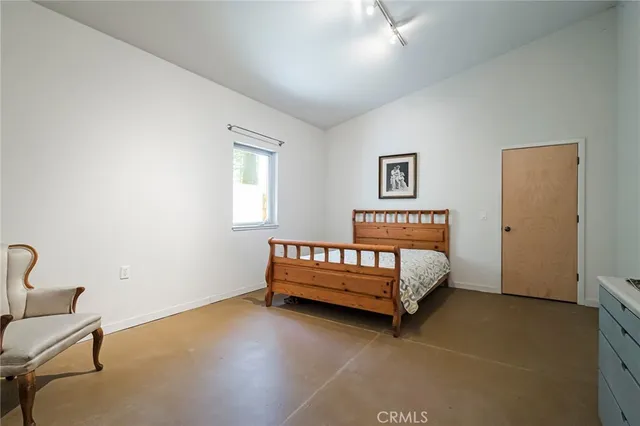 a bed sitting in a bedroom next to a window with a chair