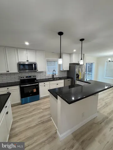 a kitchen with stainless steel appliances granite countertop a sink a stove and a wooden floors
