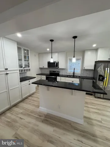 a large kitchen with granite countertop a sink a counter space appliances and cabinets