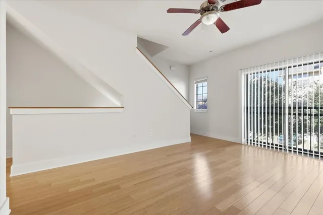 a view of a room with wooden floor fan and windows