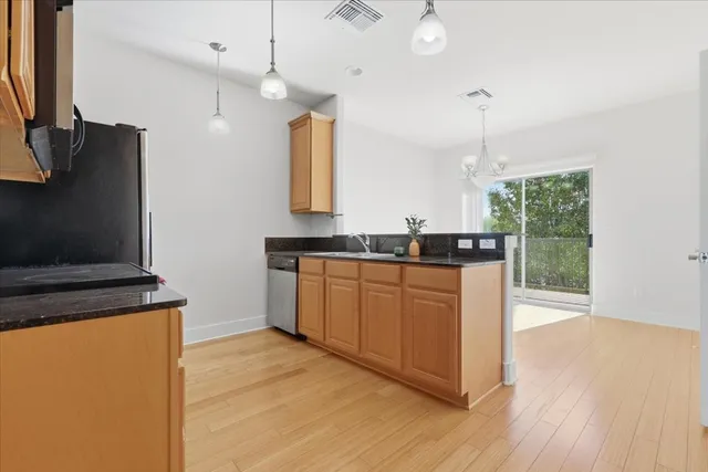 a kitchen with granite countertop a stove a sink and a wooden floor