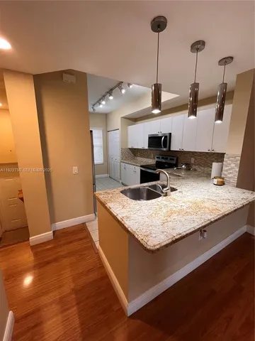 a kitchen with stainless steel appliances granite countertop a sink stove and wooden floor