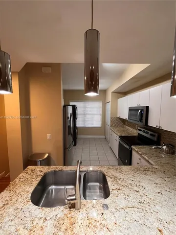 a kitchen with stainless steel appliances kitchen island a stove a sink and a refrigerator