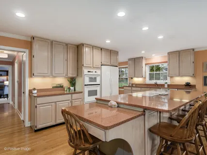a kitchen with stainless steel appliances granite countertop a stove top oven a refrigerator a sink and chairs