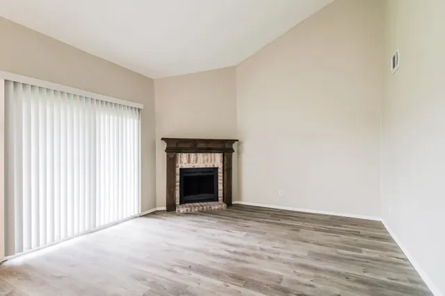 a view of an empty room with a fireplace and a window