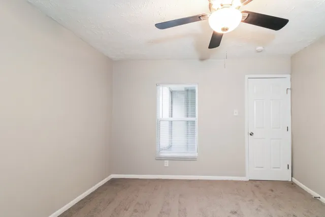an empty room with a window and ceiling fan