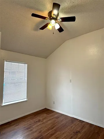 an empty room with wooden floor chandelier fan and windows