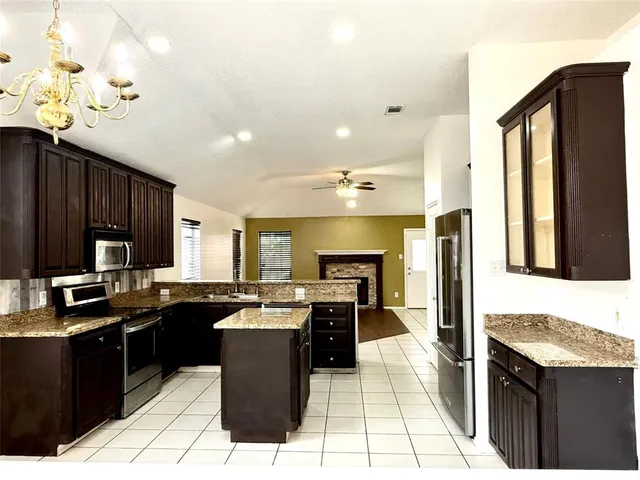 a kitchen with granite countertop a sink a counter top space appliances and cabinets