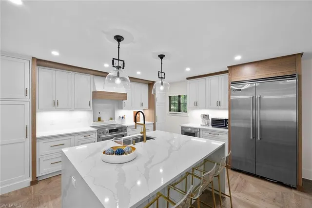 a kitchen with stainless steel appliances granite countertop a sink a stove a refrigerator and island