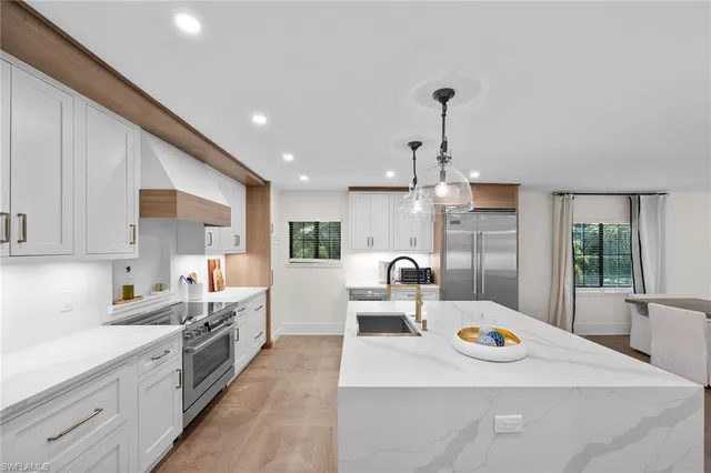 a large kitchen with kitchen island a large counter space a sink appliances and cabinets