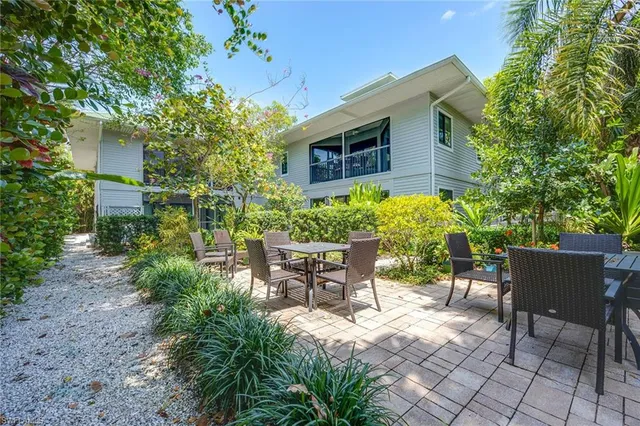a patio with table and chairs and potted plants