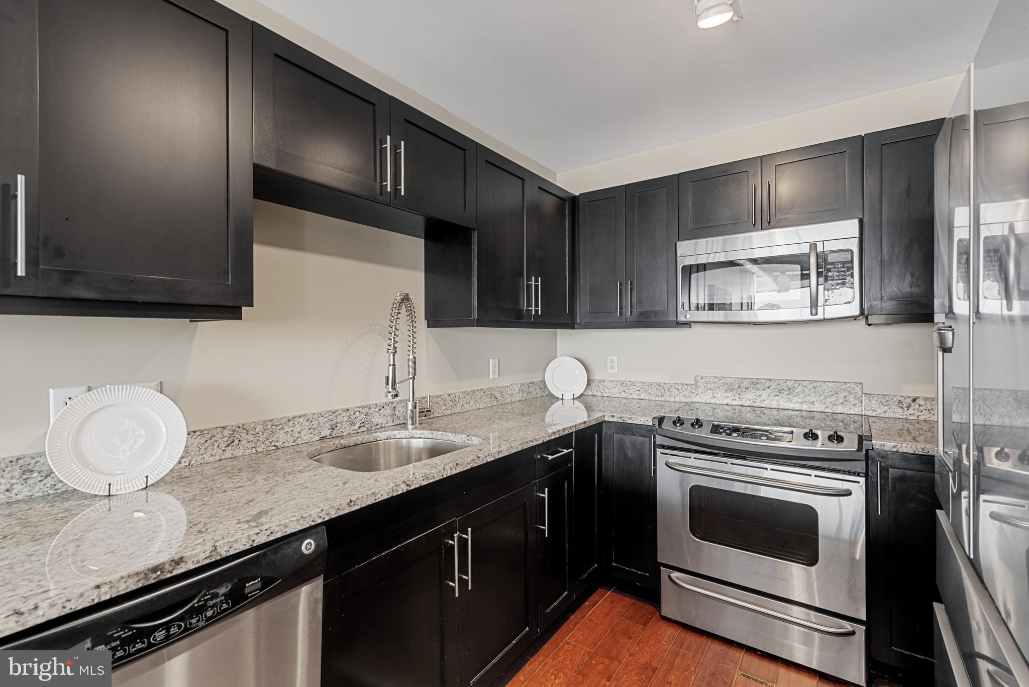 1200 Steuart Street, Unit 416 Baltimore, MD 21230 - Photo 17 of 37 a kitchen with granite countertop a stove sink and cabinets