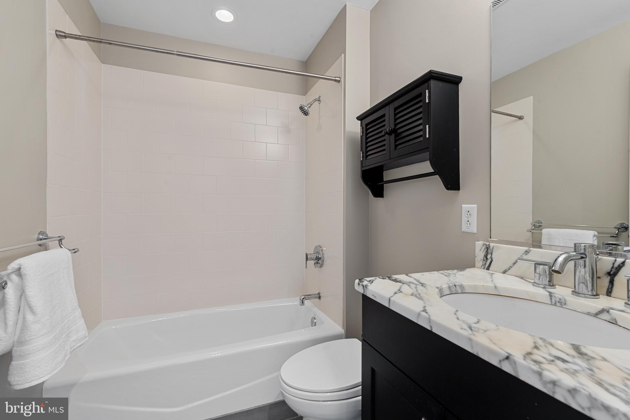 1200 Steuart Street, Unit 416 Baltimore, MD 21230 - Photo 22 of 37 a bathroom with a granite countertop sink a toilet a mirror and shower