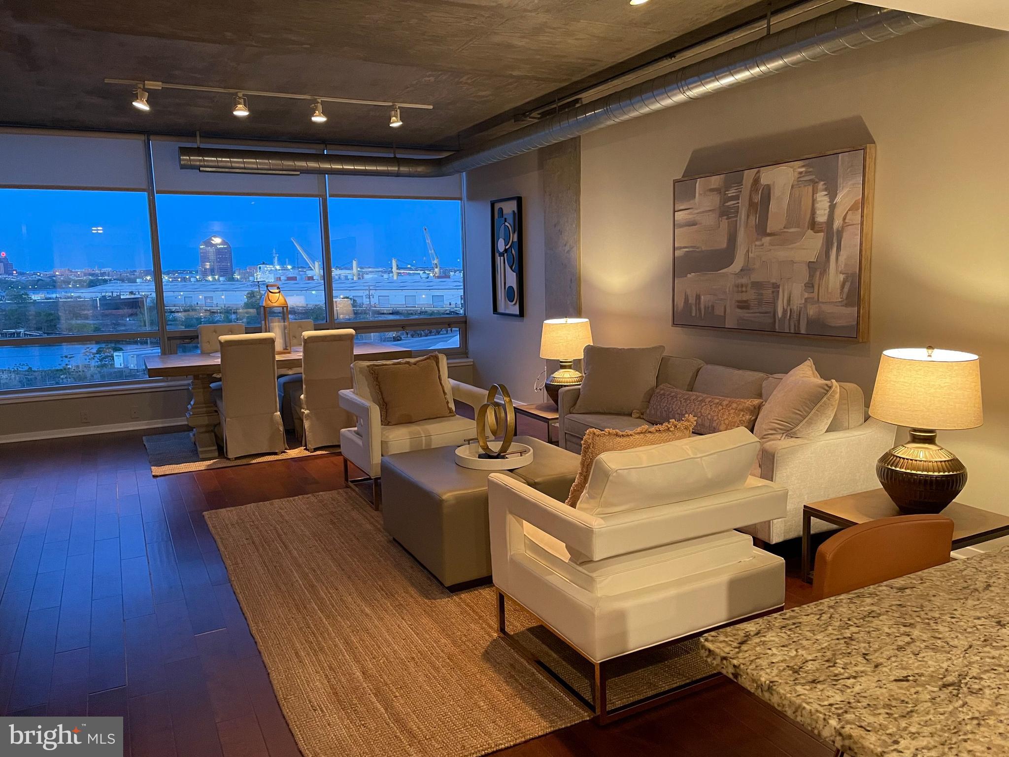 1200 Steuart Street, Unit 416 Baltimore, MD 21230 - Photo 33 of 37 a living room with couches chairs and kitchen view with wooden floor