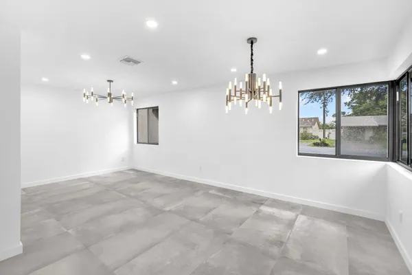 a view of an empty room with window and chandelier