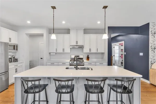 a kitchen with stainless steel appliances a dining table chairs and white cabinets