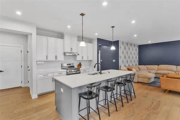 a kitchen with stainless steel appliances kitchen island granite countertop a sink a stove a dining table and chairs