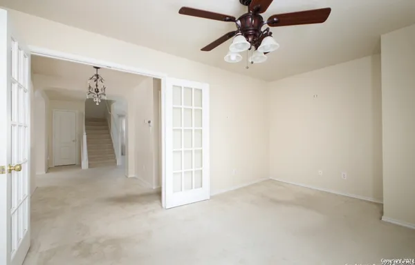 an empty room with windows and chandelier fan