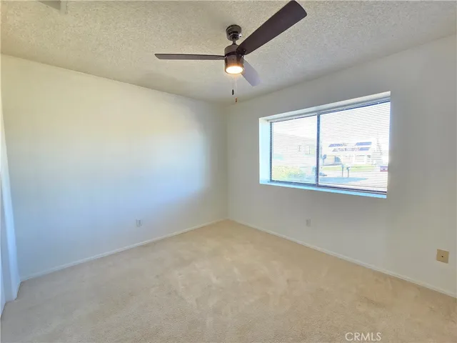 an empty room with windows and ceiling fan