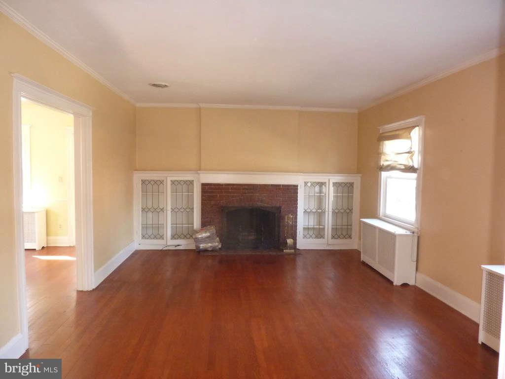 2435 Everton Road Baltimore, MD 21209 - Photo 4 of 28 an empty room with wooden floor fireplace and windows