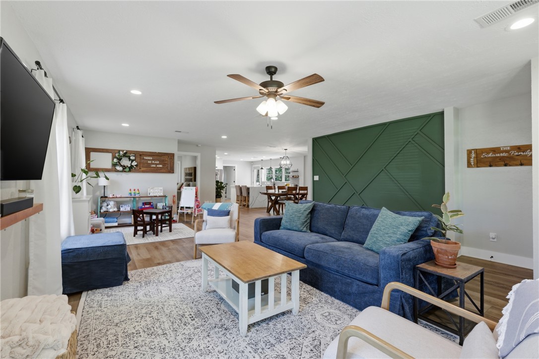 515 Crescent Drive Bryan, TX 77801 - Photo 9 of 43 Open-concept living area with wood-look LVP flooring, a decorative accent wall, recessed lighting, and a ceiling fan