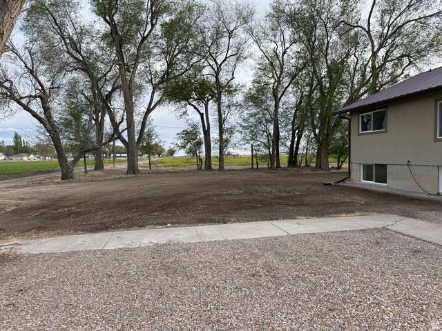 2865 North 3250 W Road Sutherland, UT 84624 - Photo 28 of 28 Spacious outdoor area featuring mature trees and a gravel driveway
