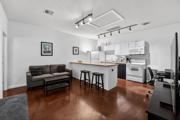 a living room with stainless steel appliances furniture and a kitchen view