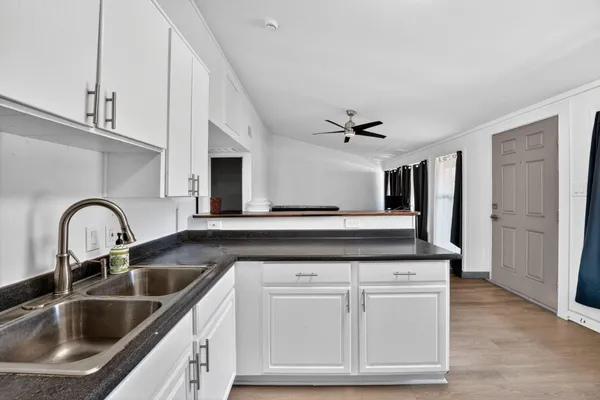 a kitchen with white cabinets and sink