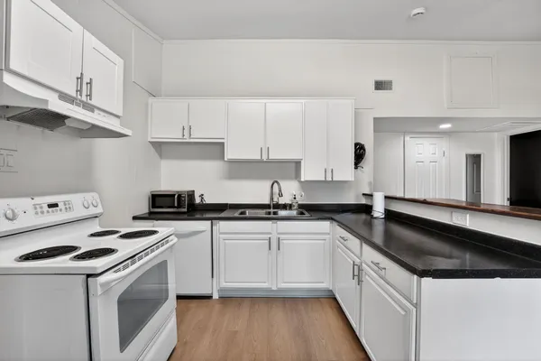 a kitchen with granite countertop a sink a stove and cabinets