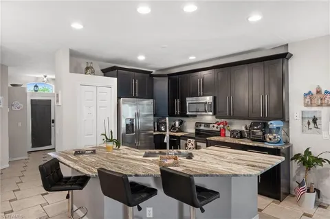 a kitchen with stainless steel appliances kitchen island granite countertop a table chairs sink refrigerator and cabinets